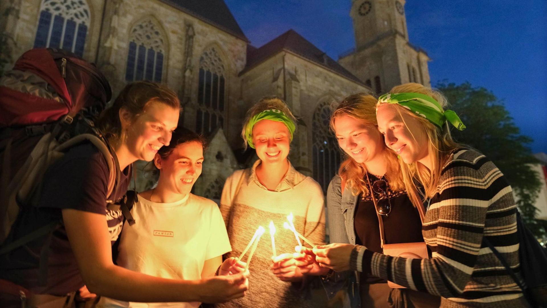 Vor der Dortmunder Reinoldikirche entzünden Teilnehmerinnen des Kirchentags gemeinsam Kerzen.