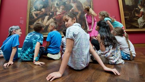 Eine Gruppe von Kindern sitzt im Rahmen eines museumspädagogischen Workshops im Frankfurter Städel Museum vor einem altmeisterlichen Gemälde.