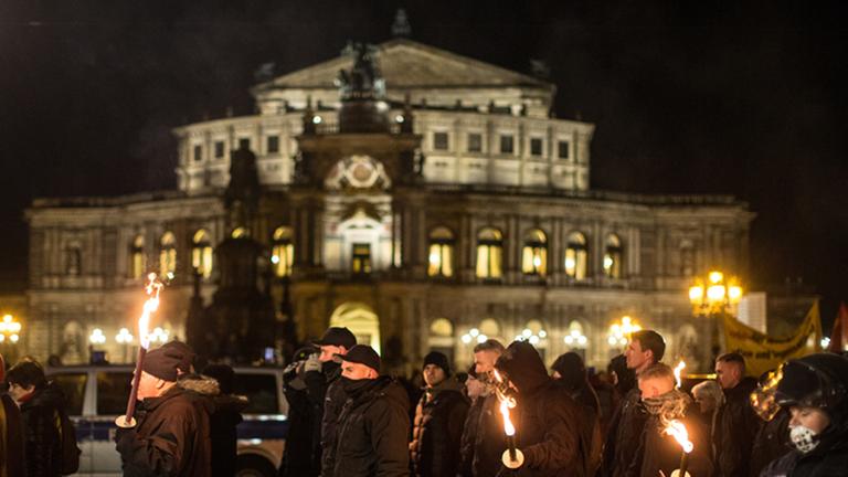 Etwa 200 Neonazis ziehen am 12.2.2014 mit Fackeln durch die Innenstadt von Dresden. Im Hintergrund ist die beleuchtete Semperoper zu sehen.
