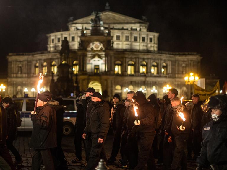 Etwa 200 Neonazis ziehen am 12.2.2014 mit Fackeln durch die Innenstadt von Dresden. Im Hintergrund ist die beleuchtete Semperoper zu sehen.