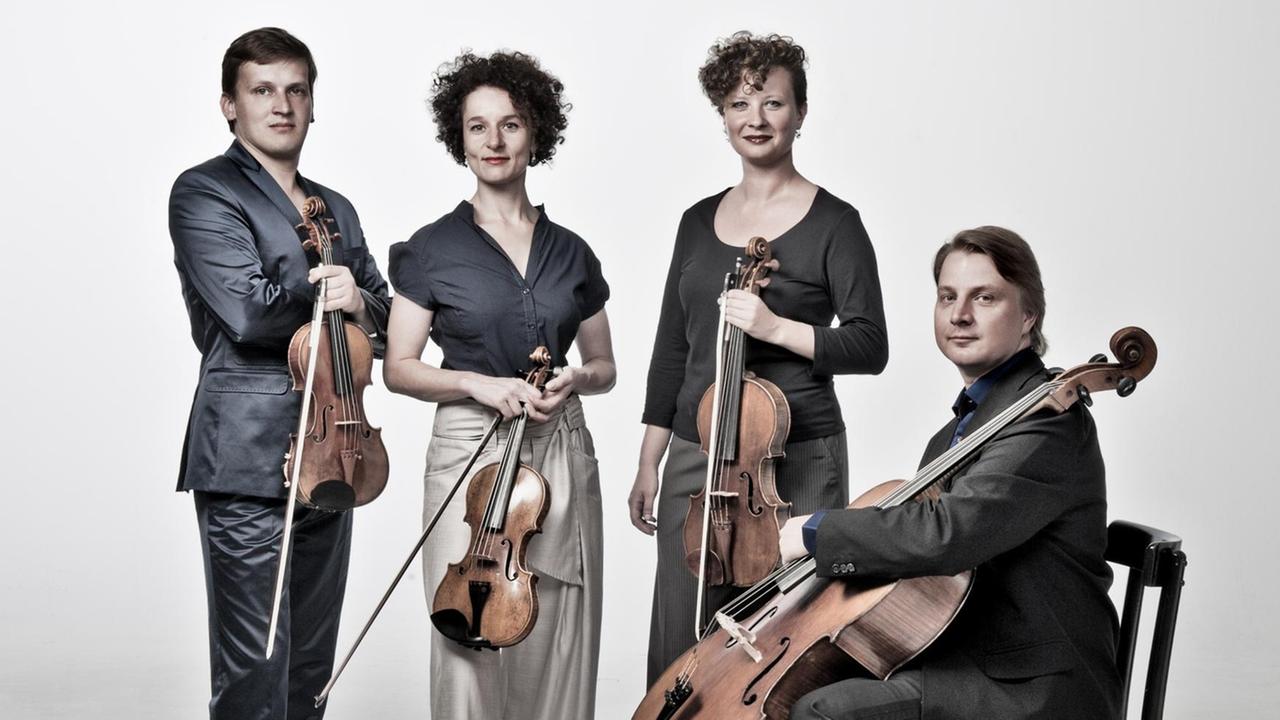 Die Musiker des Asasello-Quartetts halten ihre Instrumente in den Händen und stehen und sitzen vor weißem Hintergrund.