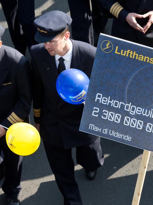 Piloten der Lufthansa protestieren am 02.04.2014 vor dem Flughafen von Frankfurt am Main (Hessen). Sie halten Ballons und ein Plakat in Händen, das auf das Lufthansa-Sparprogramm Score anspielt.