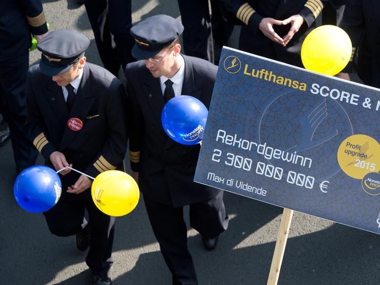 Piloten der Lufthansa protestieren am 02.04.2014 vor dem Flughafen von Frankfurt am Main (Hessen). Sie halten Ballons und ein Plakat in Händen, das auf das Lufthansa-Sparprogramm Score anspielt.