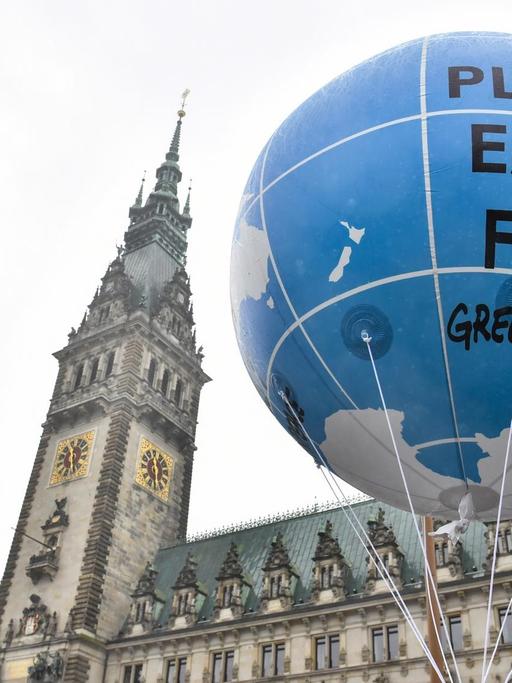 Ein Ballon mit der Aufschrift "Planet Earth First" hängt vor dem Hamburger Rathaus.