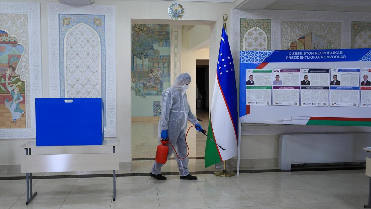 Eine Reinigungskraft mit Schutzanzug desinfiziert ein Wahllokal in Usbekistan Eine Reinigungskraft mit Schutzanzug desinfiziert ein Wahllokal in Usbekistan