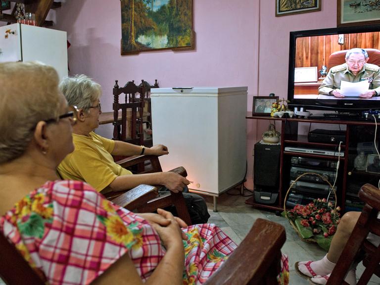 Mehrere kubanische Frauen sitzen vor dem Fernseher, in dem Staatspräsident Raúl Castro bei einer Ansprache zu sehen ist.