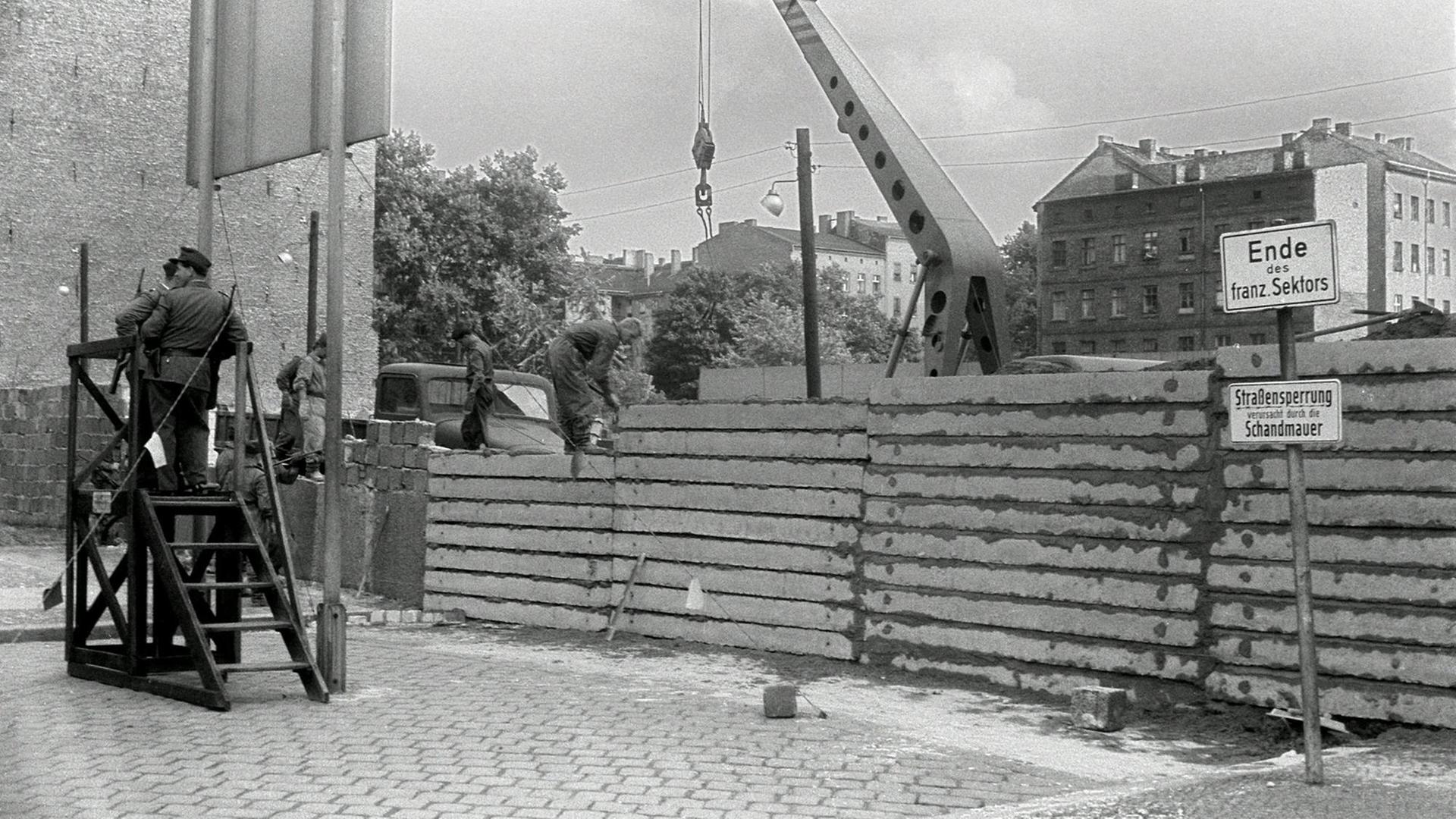 Unter der Aufsicht von bewaffneten Volkspolizisten errichtet eine Ostberliner Maurerkolonne am 18.8.1961 an der sowjetisch-amerikanischen Sektorengenze am Potsdamer Platz eine mannshohe Mauer.