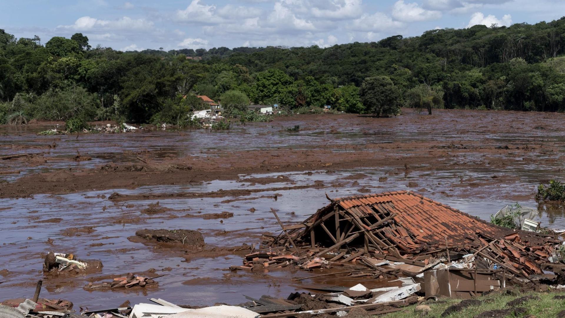 Das Foto zeigt eine braune Schlammflut und Trümmer eines Gebäudes nach einem Dammbruch in Brasilien.