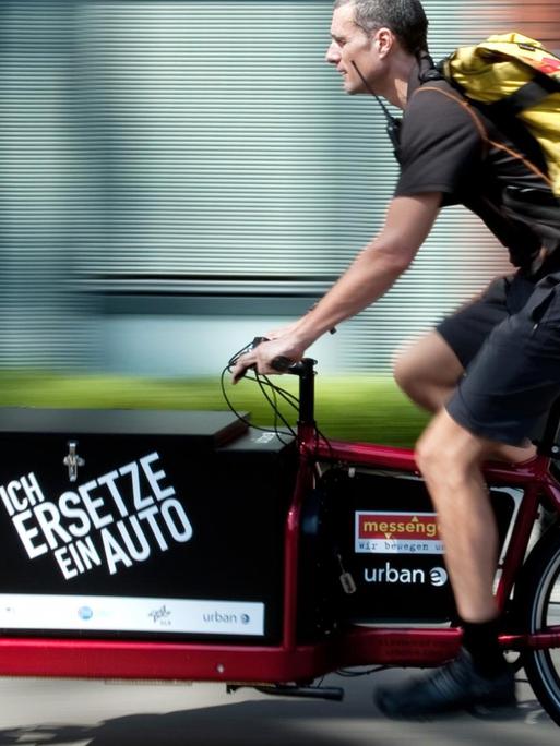 Ein Fahrradkurier fährt auf dem Gelände des EUREF-Campus in Berlin-Schöneberg mit einem Elektrofahrrad namens Lasten-E-Bike iBullitt