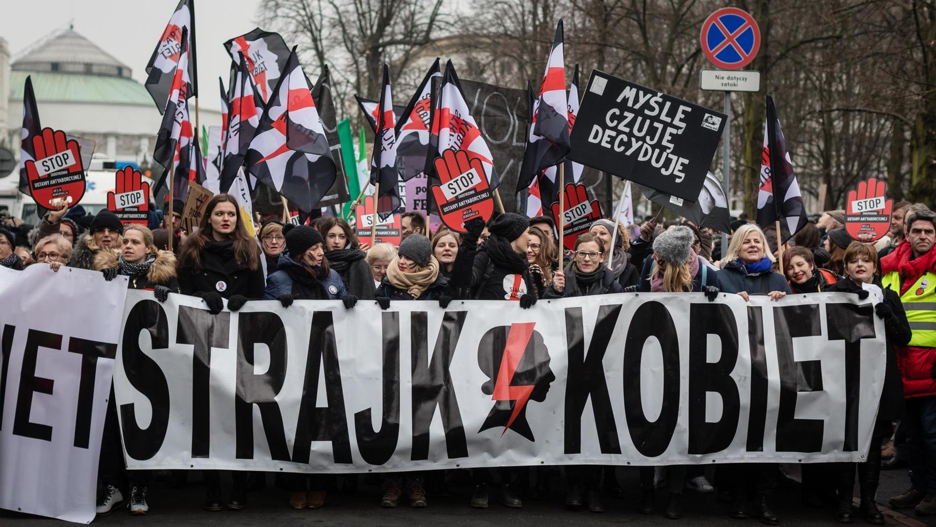 In Warschau ziehen Demonstranten mit einem großen Transparent gegen eine Verschärfung des Abtreibungsrechts durch die Straßen.