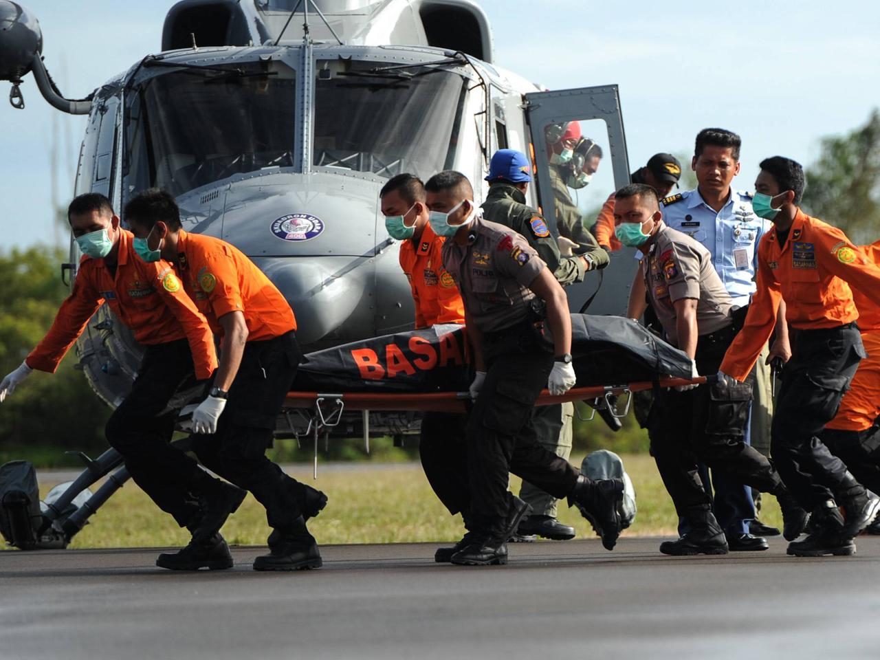 Einsatzkräfte tragen ein Opfer des Flugzeugabsturzes aus einem Helikopter auf einem indonesischen Militärstützpunkt.