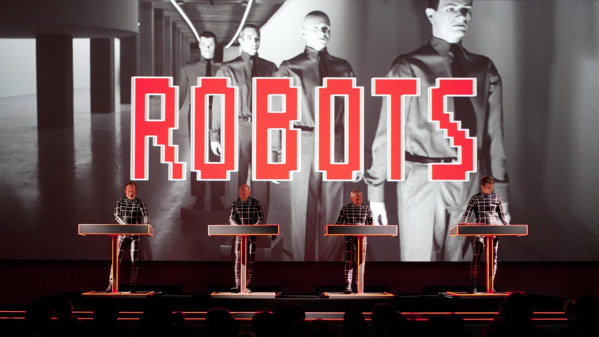 Die vier Musiker von Kraftwerk stehen auf der Bühne, hinter ihnen ein roter "Roberts" Schriftzug