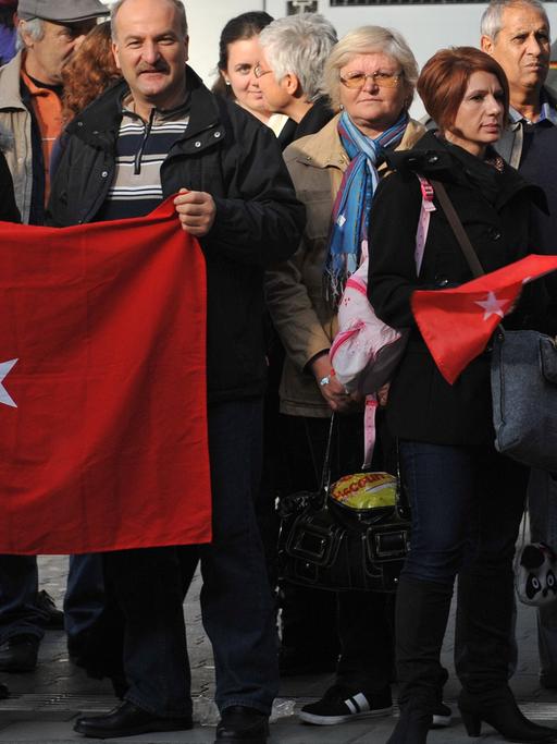 Menschen mit türkischen und deutschen Flaggen warten im Hauptbahnhof in München auf die Ankunft des Erinnerungszuges "50 Jahre Migration".