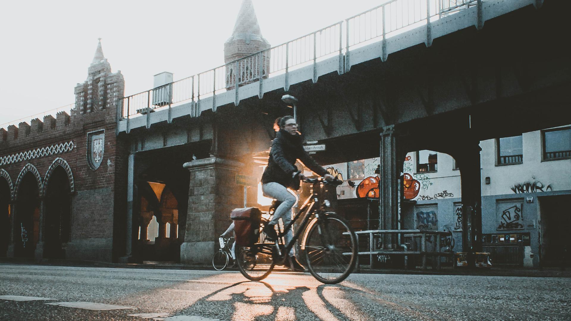 Eine Radfahrerin fährt in Berlin dei Oberbaumbrücke entlang.