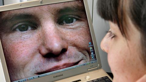 Das Bild eines jungen Mannes sieht sich diese Frau auf einem Laptop an.