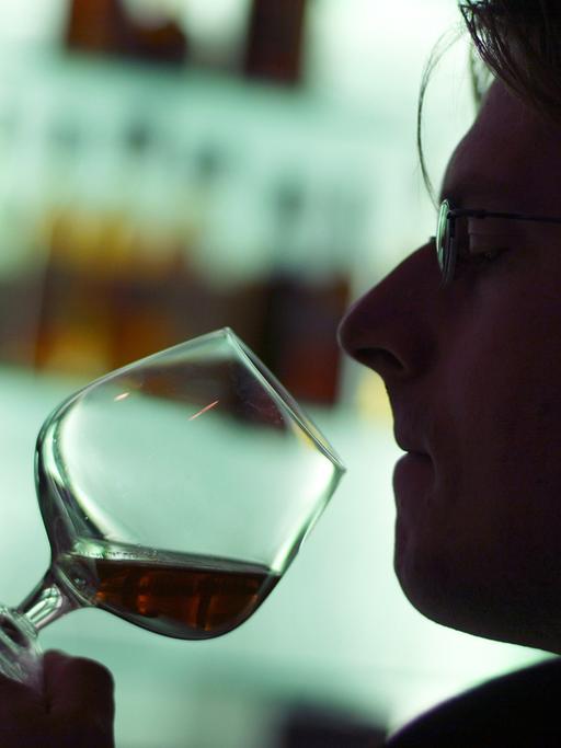 Ein Mann riecht an einem Glas Cognac in einer Hotelbar in München.