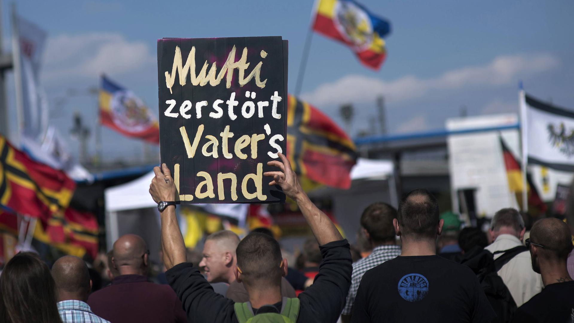 Auf einer Demonstration rechter Gruppen in Berlin am 30. Juli 2016 hält ein Demonstrant ein Plakat mit der Aufschrift "Mutti zerstoert Vaters Land" hoch.