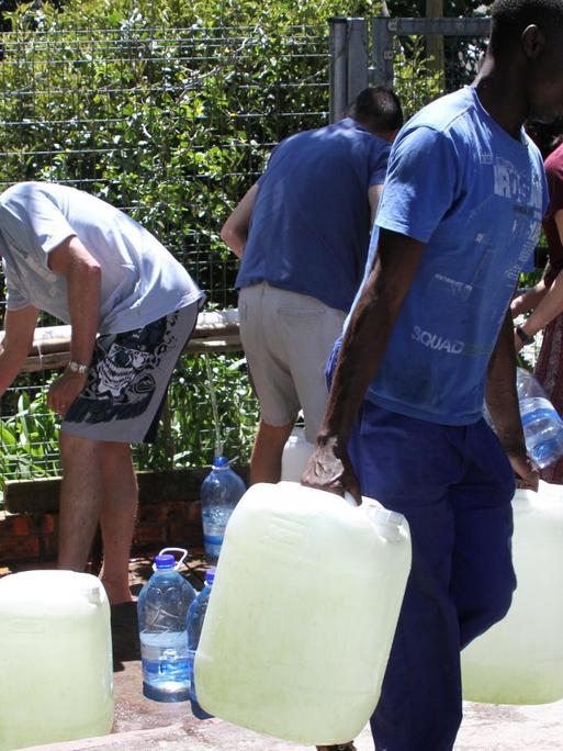 Bürger füllen am 15.12.2017 Wasserkanister an einer natürlichen Quelle in Kapstadts Vorort Newlands auf. In Südafrikas Touristen-Metropole Kapstadt wird die Wassserversorgung wegen einer anhaltenden Dürre nochmals drastisch reduziert.