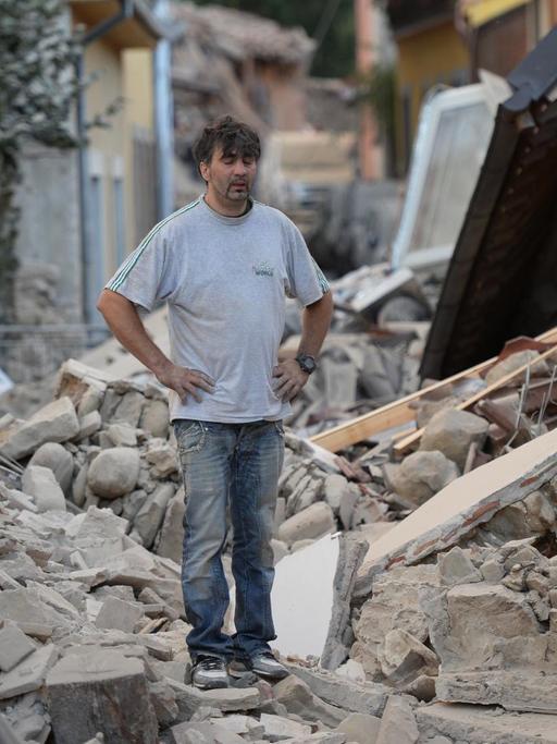 Ein Mann steht zwischen Trümmern.