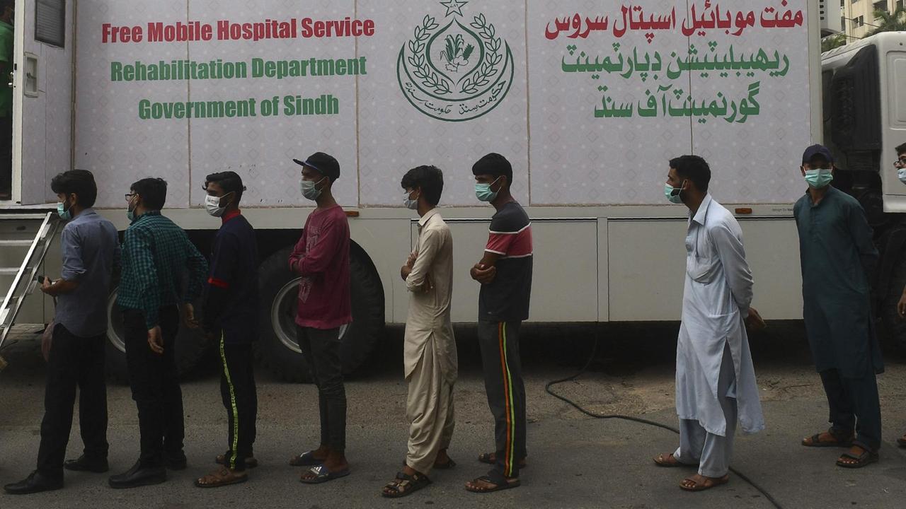 In der pakistanischen Millionenstadt Karatschi stehen Hafenarbeiter für eine Impfung gegen das Coronavirus an. Es handelt sich um eine mobile Impfstation der Provinzregierung Sindh.