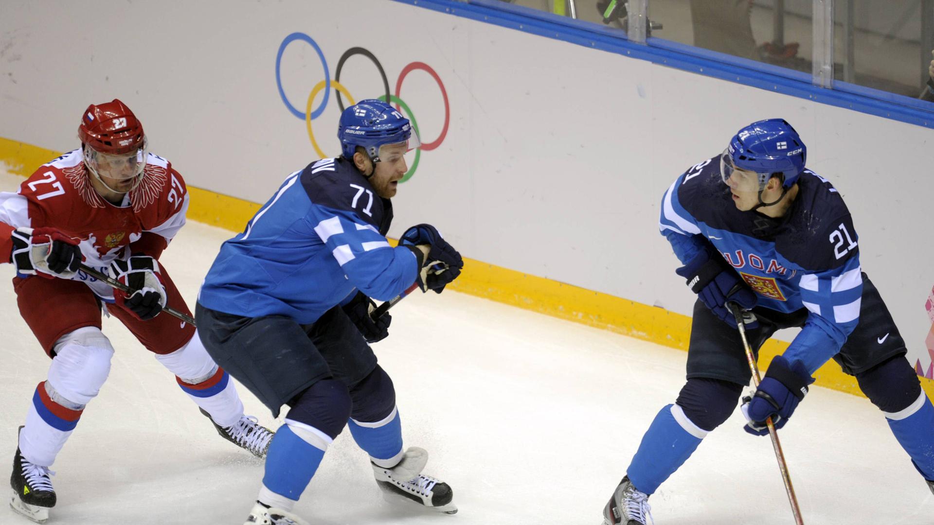 Drei Eishockeyspieler in Aktion: links der Russe Tereshenko, rechts die Finnen Komarov und Lehterä mit dem Puck Drei Eishockeyspieler in Aktion: links der Russe Tereshenko, rechts die Finnen Komarov und Lehterä mit dem Puck