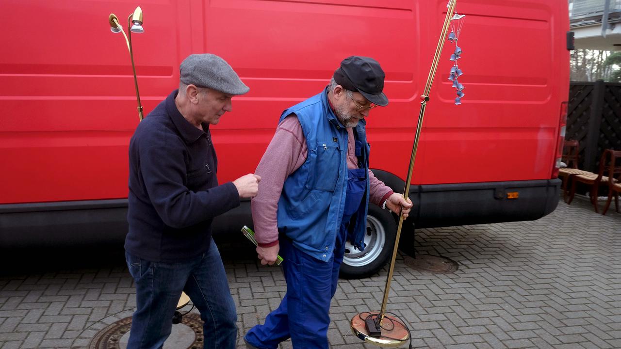 Heinicke (l.) und Aleks mit Lampen in der Hand vor einem roten Lieferwagen