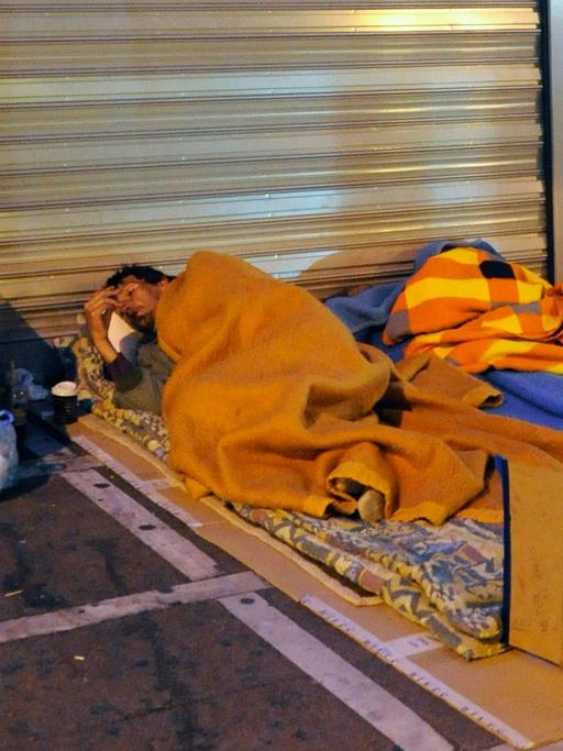 Ein Obdachloser liegt auf seinem Schlafplatz auf dem Bürgersteig vor einer Filiale der Emporiki Bank in Athen