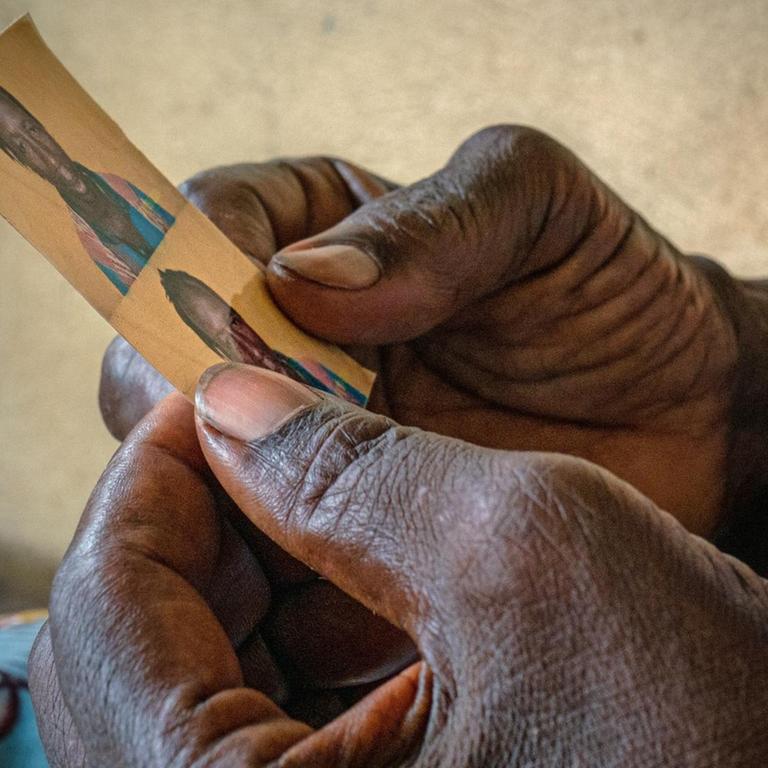 Eine Mutter in Conakry (Guineia) hält in ihren Händen das Foto ihres Sohnes, der die Reise nach Europa aus unbekannten Gründen nicht überlebte.