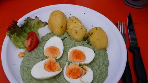 Auf einem Teller ist grüne Soße mit Kartoffeln, Ei und Salat angerichtet.