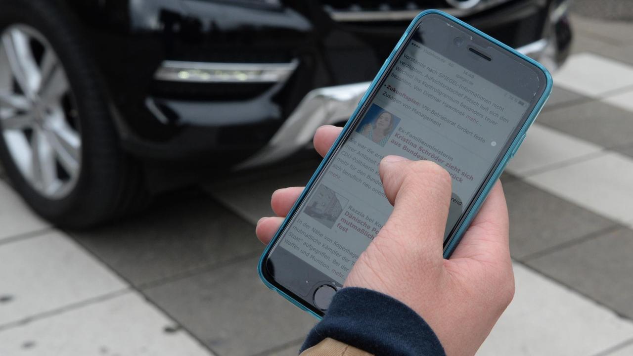 ILLUSTRATION - Eine Hand mit einem Smartphone ist am 07.04.2016 in Stuttgart (Baden-Württemberg) vor einer befahrenen Straße zu sehen. Foto: Franziska Kraufmann/dpa (zu dpa "Studie: Viele Fußgänger durch Smartphones abgelenkt" vom 08.04.2016) | Verwendung weltweit