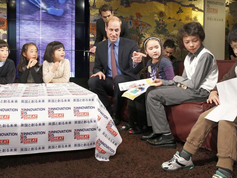 Der britische Prinz William spricht mit Kindern in einem Buchladen in Tokios Daikanyama-Viertel.