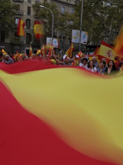 Demonstranten fordern in Barcelona vor dem Referendum die Einheit Spaniens und tragen eine riesige gelb-rote Fahne.