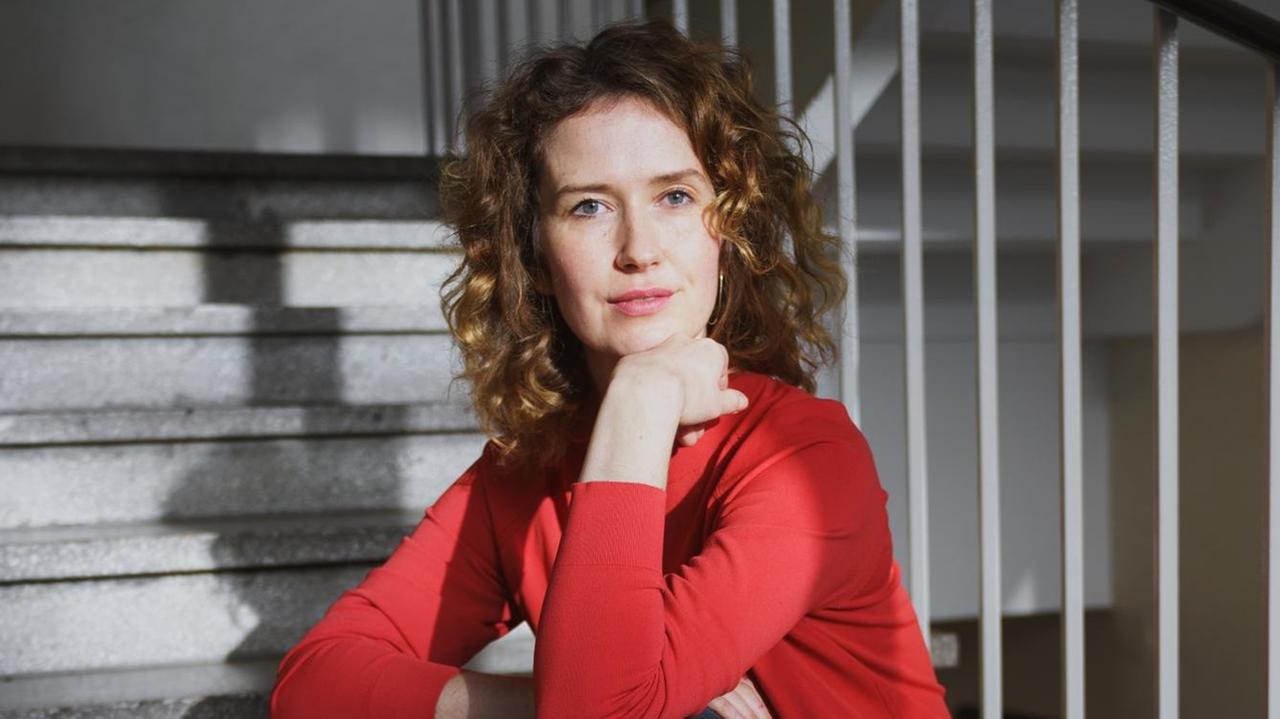 Autorin Katja Lewina sitzt in einem Treppenhaus.