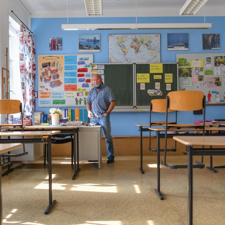 Ein leeres Klassenzimmeer mit blau gestrichener Wand und viel Dekoration.