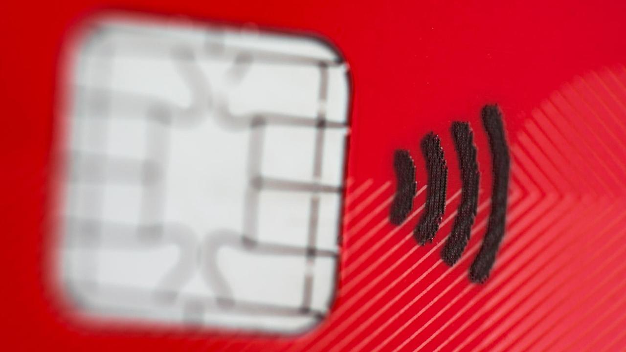 Eine rote EC-Karte mit einem Funkchip und einem Symbol ähnlich dem W-Lan-Symbol für kontaktloses Bezahlen.