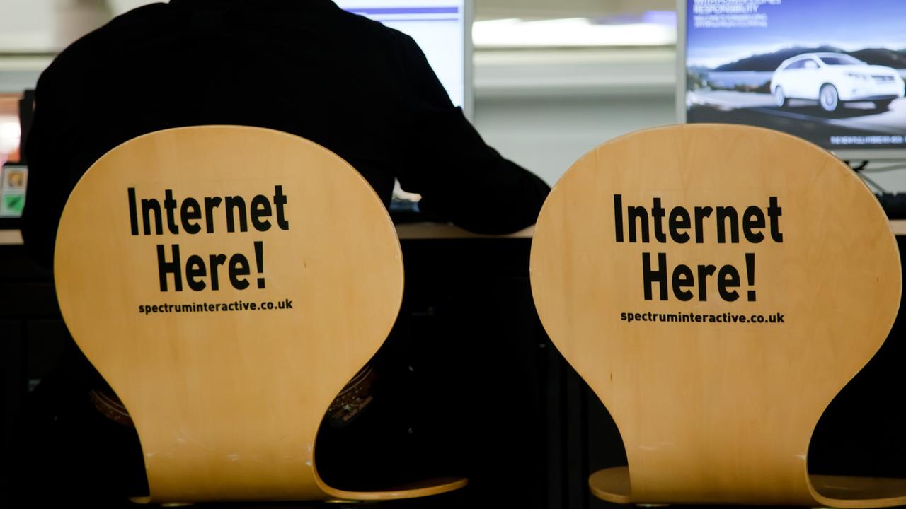 Ein Mann sitzt auf einem Stuhl, auf dessen Rückenlehne "Internet here!" steht.