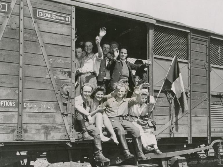 Französische Zwangsarbeiter winken nach der Befreiung durch die Alliierten aus einem Eisenbahnwaggon.