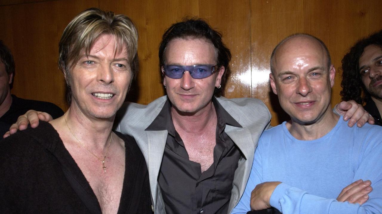 David Bowie, Bono und Brian Eno gemeinsam auf einem Foto von 2002. 