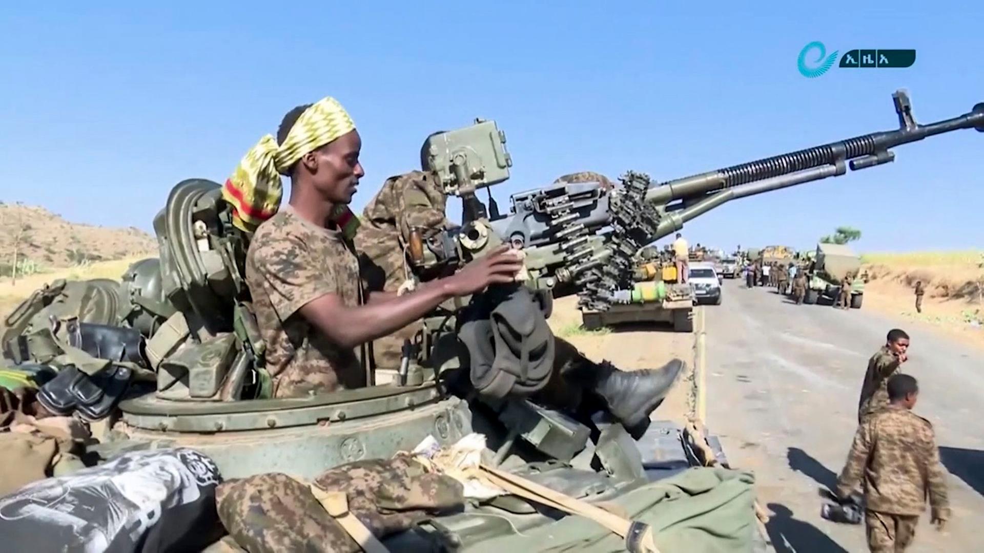 Ein Soldat mit einer Waffe sitzt auf einem Militär-Laster.