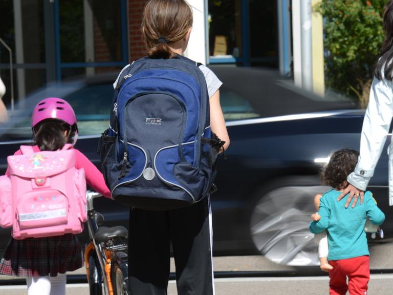 Schulkinder und ihre Mütter überqueren einen Zebrastreifen