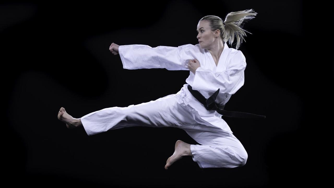 Eine Frau im weißen Taekwondo Anzug in Verteidigungsposition.
