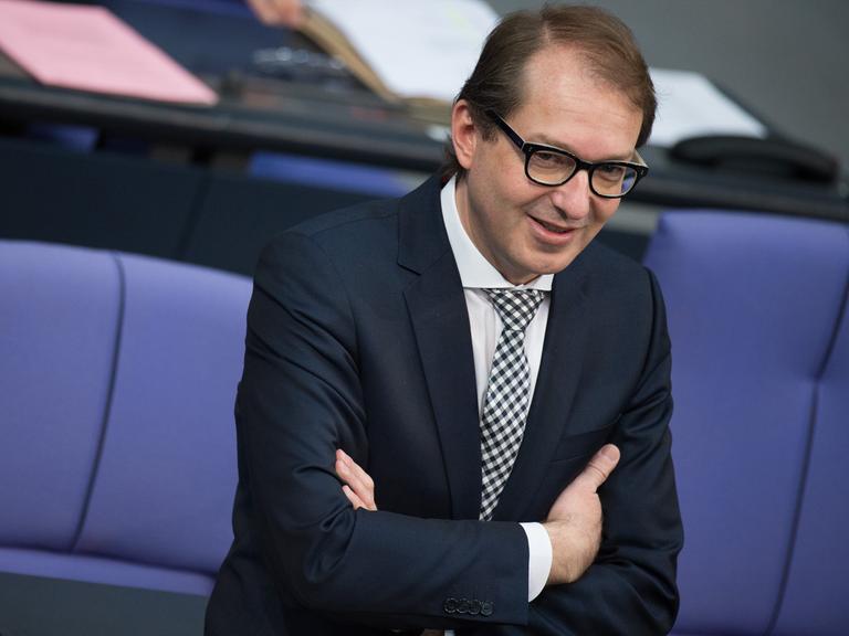 Bundesverkehrsminister Alexander Dobrindt (CSU) steht mit verschränkten Armen im Plenarsaal des Bundestags.