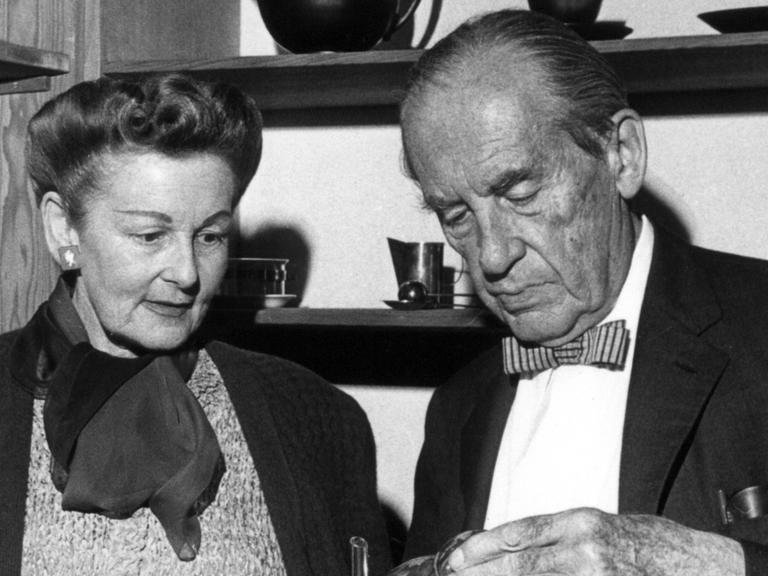 Der Architekt Walter Gropius betrachtet mit seiner Frau Ise während der Eröffnung des von ihm angeregten Bauhaus-Archivs im Ernst-Ludwig-Haus auf der Darmstädter Mathildenhöhe am 8. April 1961 eine Metallkanne aus den Bauhaus-Werkstätten.