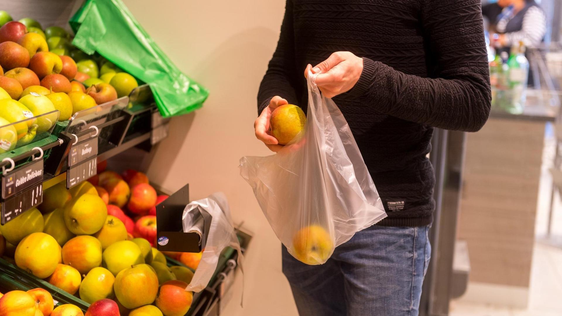 Ein Mann packt in einem Supermarkt in Flensburg Obst in einen Plastikbeutel