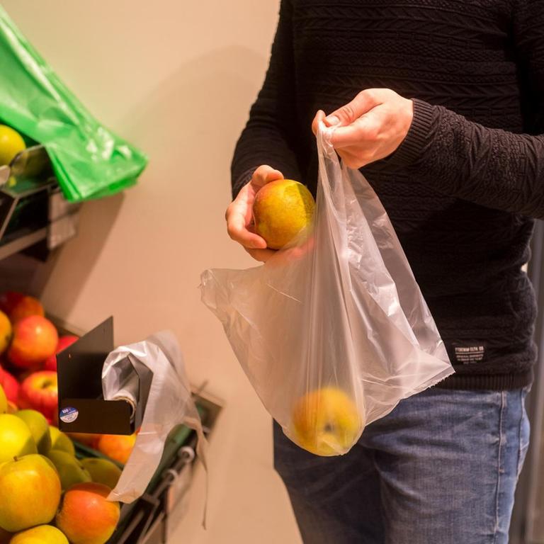 Ein Mann packt in einem Supermarkt in Flensburg Obst in einen Plastikbeutel 