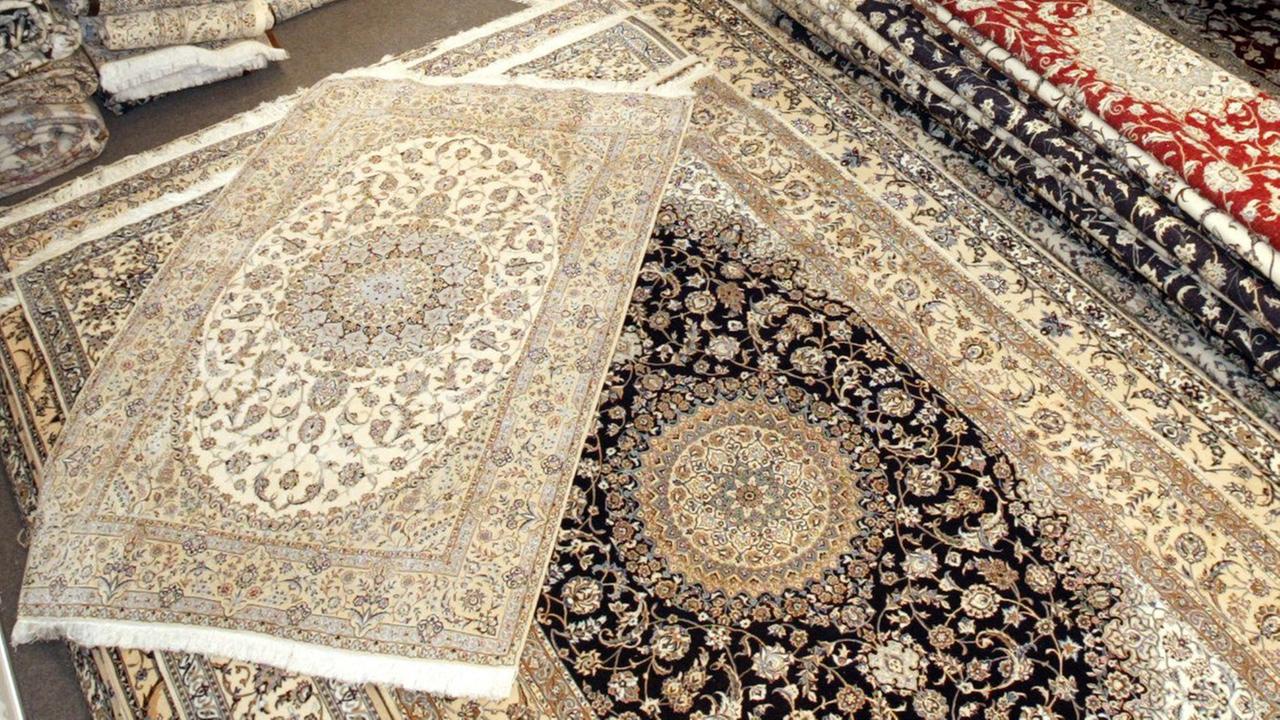 Perser-Teppiche werden von Mitarbeitern eines Ausstellers aus dem Iran in Hannover vor Beginn der Teppich-Messe Domotex sortiert