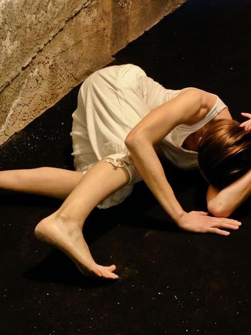 In einem engen Flur windet sich eine Frau auf dem Boden.