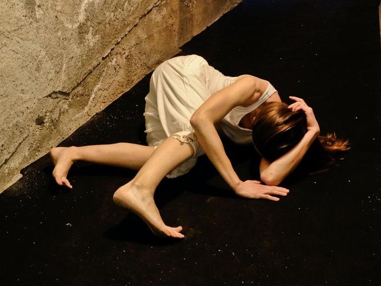 In einem engen Flur windet sich eine Frau auf dem Boden.