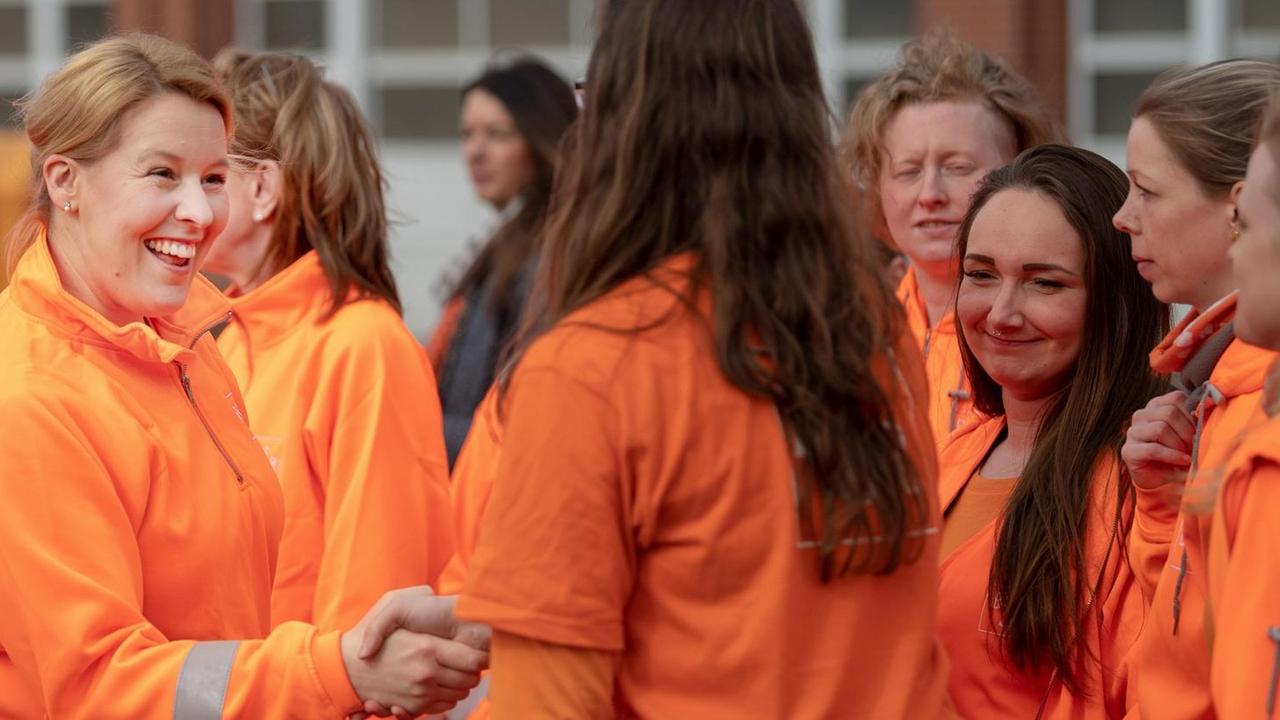 Franziska Giffey (SPD), Bundesfamilienministerin, begrüßt Müllwerkerinnen und trägt dabei auch einen orangenen Anzug