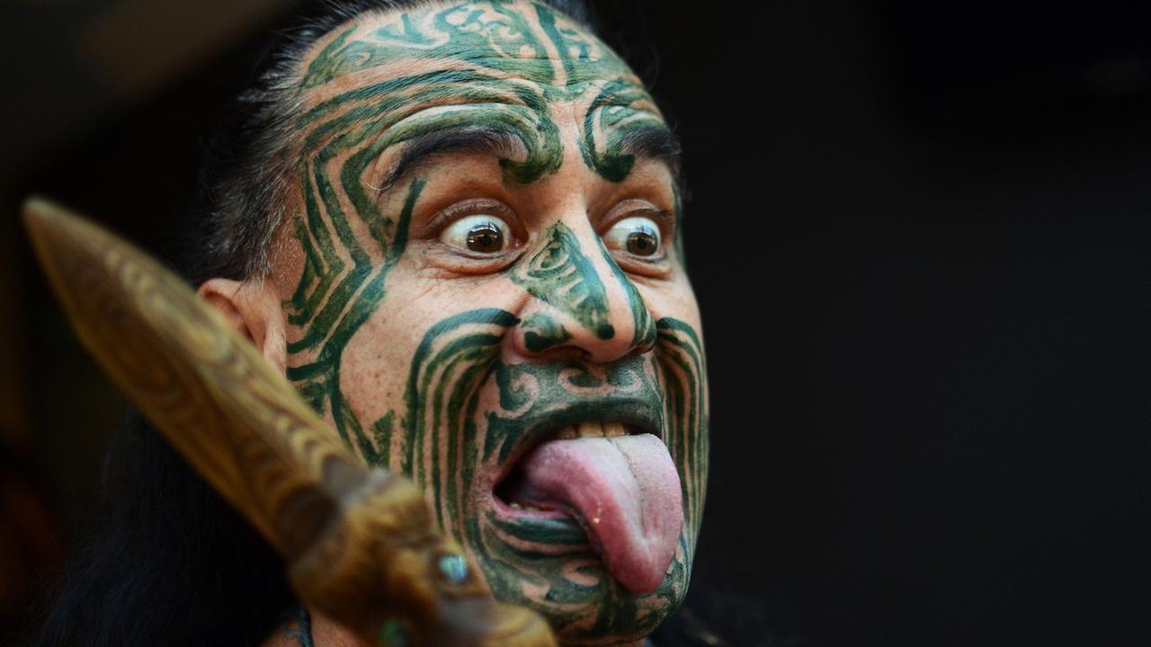 Ein Maori mit einer typischen Gesichtsbemalung und Grimasse.